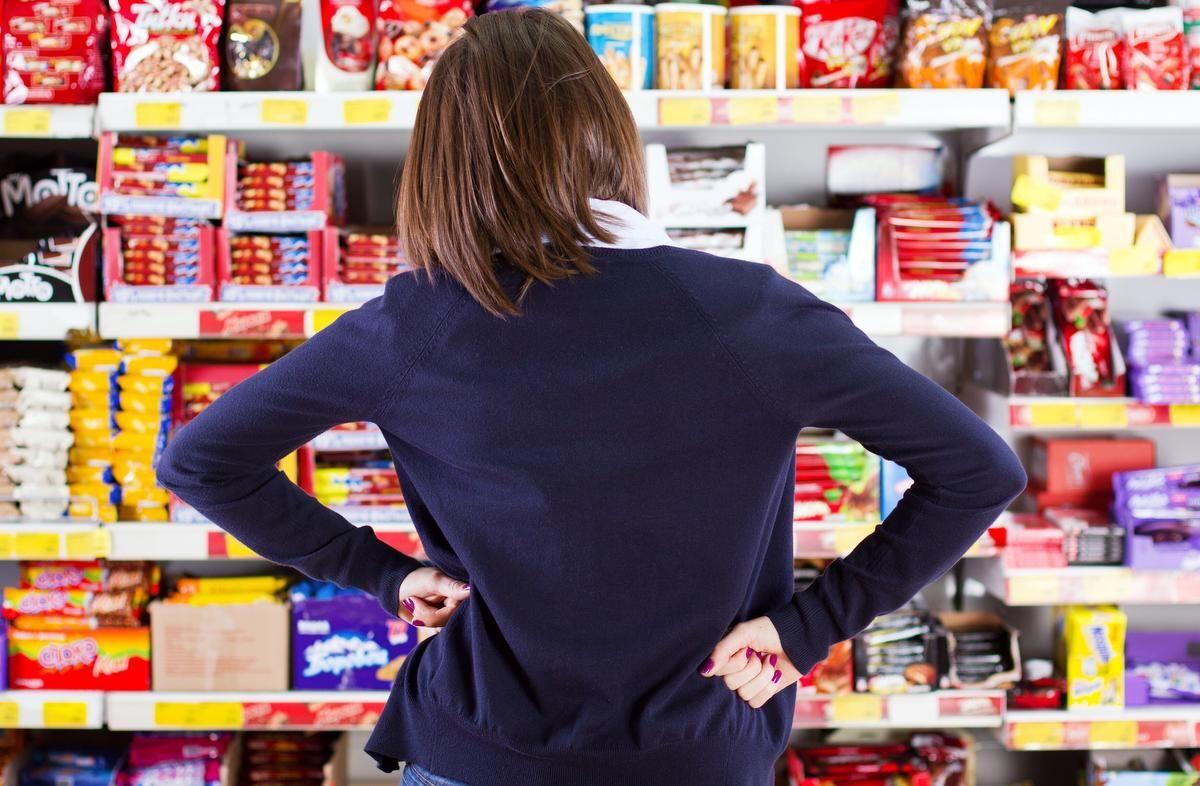 woman looking at grocery store shelf with hands on hips